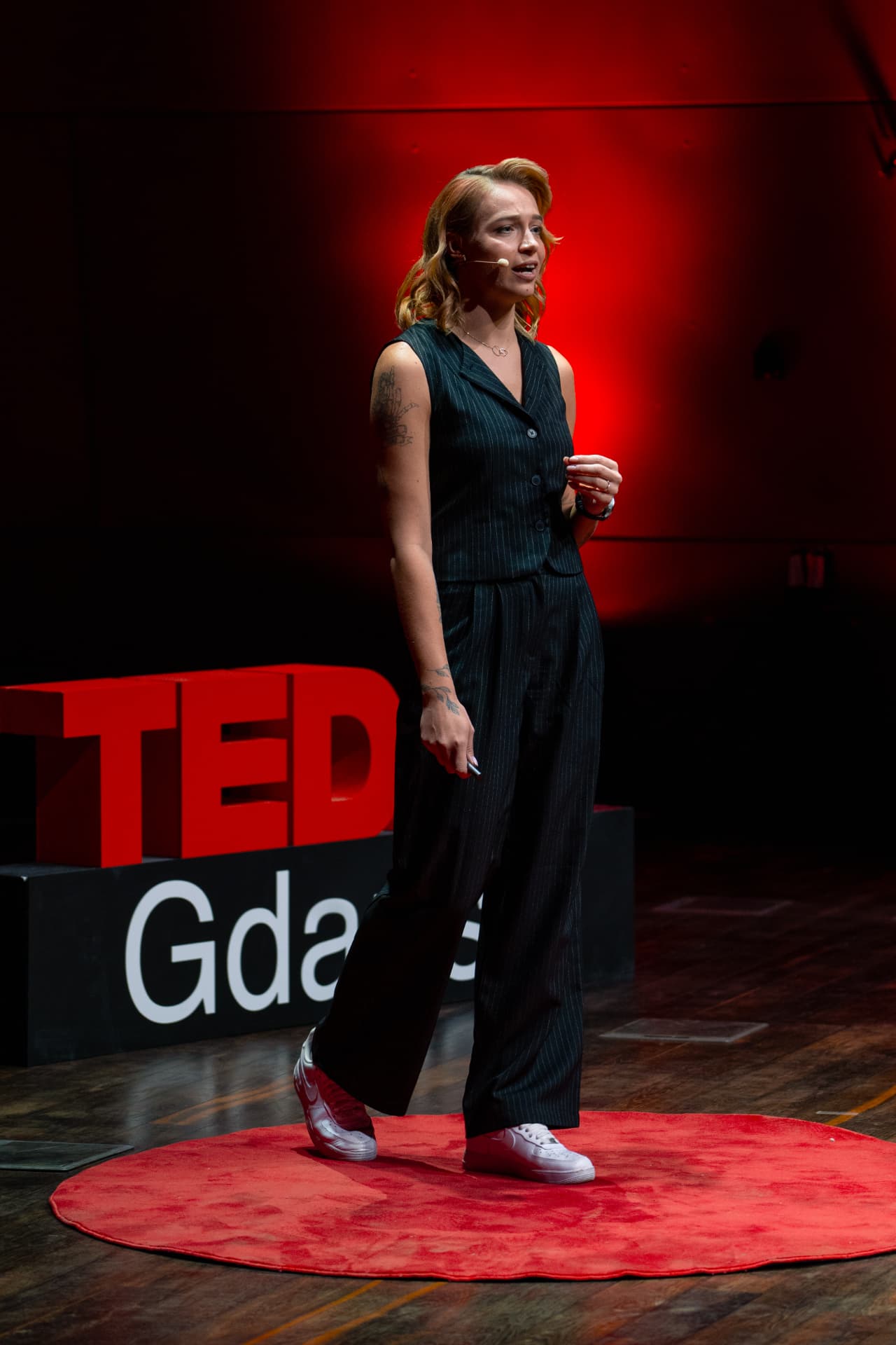 Kama Kotowska na scenie TEDx Gdańsk, na czerwonym dywanie, podczas wystąpienia